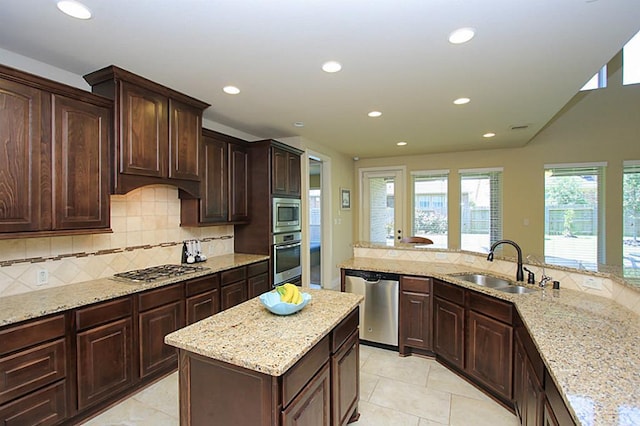 27827 Ramble Rock Ct, Katy, TX 77494 - kitchen featuring appliances with stainless steel finishes, a sink, recessed lighting, backsplash, and light stone countertops