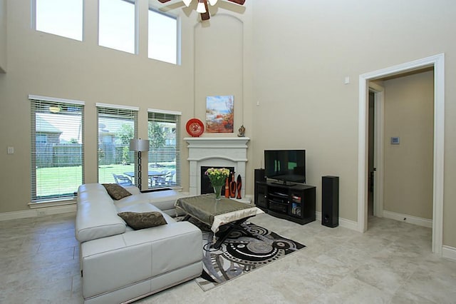27827 Ramble Rock Ct, Katy, TX 77494 - living room featuring a ceiling fan, a fireplace, a towering ceiling, and baseboards