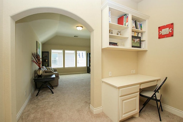 27827 Ramble Rock Ct, Katy, TX 77494 - office area featuring light carpet, arched walkways, lofted ceiling, built in desk, and baseboards