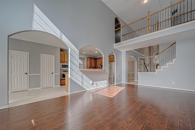 unfurnished living room with a high ceiling and light hardwood / wood-style flooring