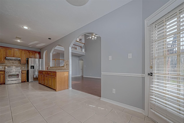 kitchen featuring sink, ceiling fan, decorative backsplash, appliances with stainless steel finishes, and light tile patterned flooring