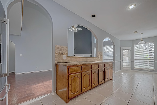 kitchen featuring ceiling fan, stainless steel fridge, pendant lighting, decorative backsplash, and light tile patterned floors