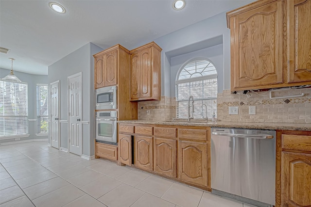 kitchen with sink, tasteful backsplash, pendant lighting, light tile patterned floors, and appliances with stainless steel finishes