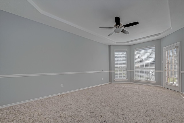 unfurnished room with a raised ceiling, ceiling fan, and carpet floors