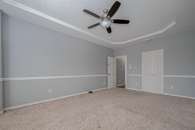 carpeted spare room with a textured ceiling, a raised ceiling, and ceiling fan