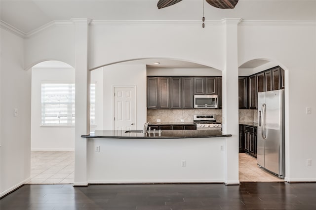 kitchen with stainless steel appliances, dark brown cabinets, and light wood-type flooring