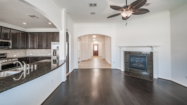 kitchen featuring hardwood / wood-style flooring, stainless steel appliances, dark stone countertops, sink, and a fireplace