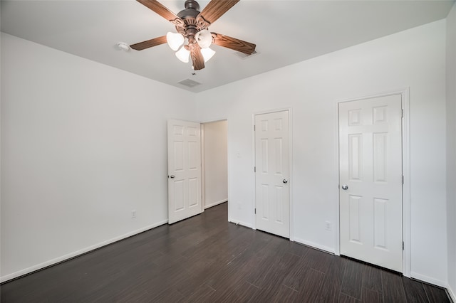 unfurnished bedroom with ceiling fan, multiple closets, and dark hardwood / wood-style floors