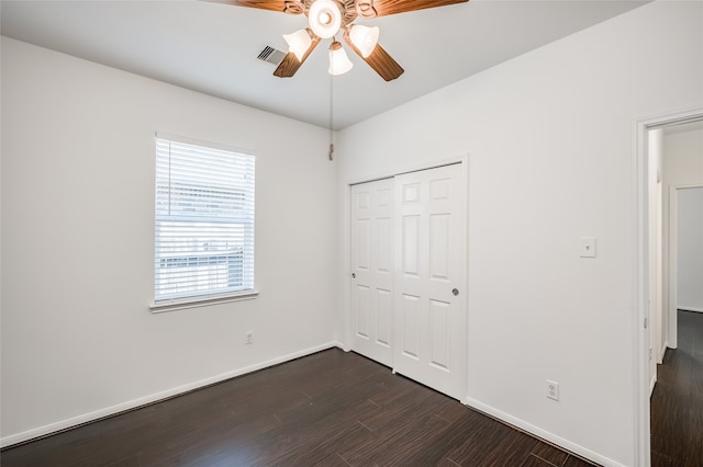 unfurnished bedroom with dark wood-type flooring, a closet, and ceiling fan