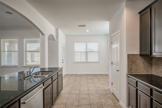 kitchen with dishwasher, dark stone countertops, sink, and dark brown cabinets