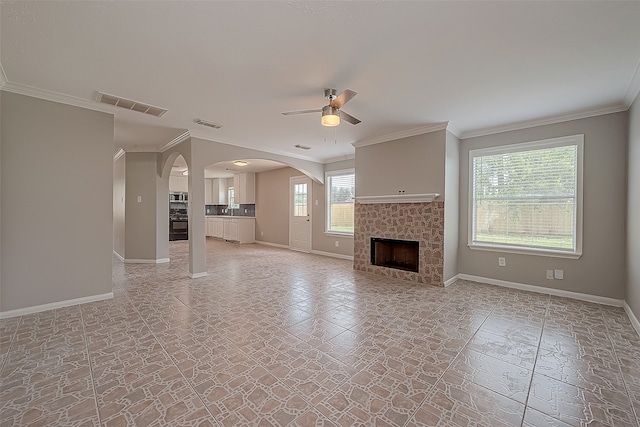 unfurnished living room with ceiling fan, crown molding, and a tiled fireplace