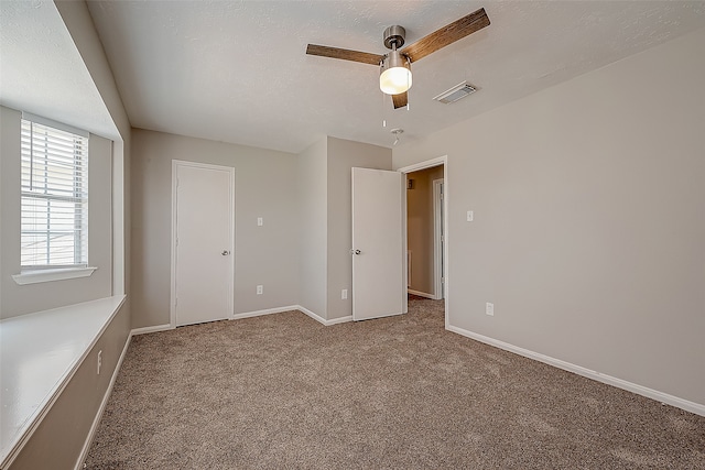 unfurnished bedroom featuring carpet flooring, a textured ceiling, and ceiling fan