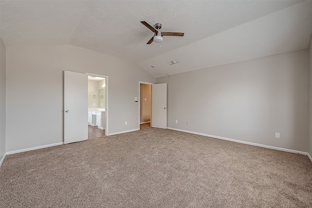 unfurnished bedroom with vaulted ceiling, connected bathroom, carpet flooring, and ceiling fan