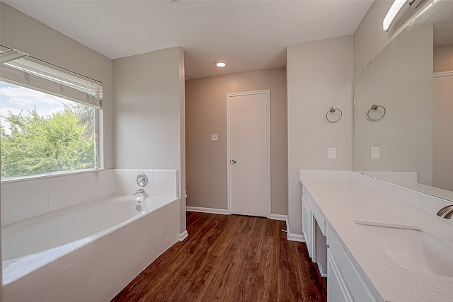 bathroom with vanity, a bath, and wood-type flooring