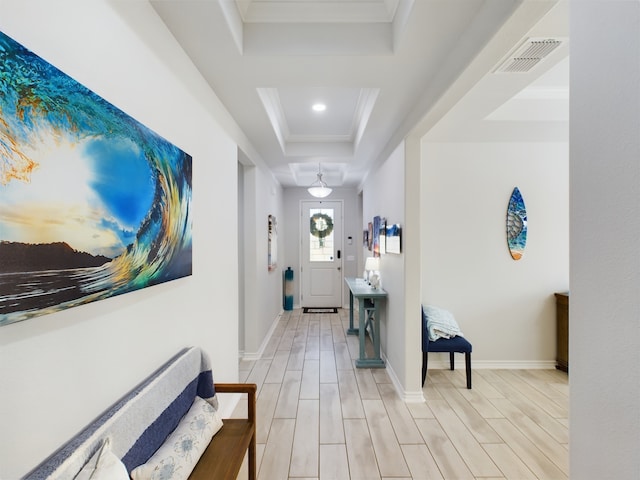 hallway featuring light hardwood / wood-style flooring, crown molding, and a tray ceiling