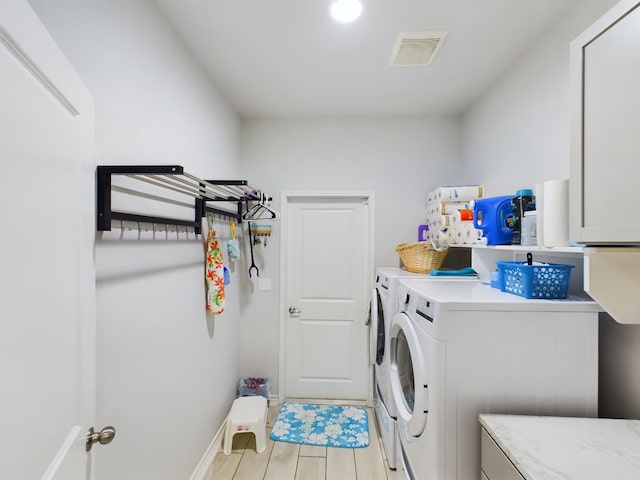 laundry room with cabinets, light hardwood / wood-style flooring, and washer and dryer