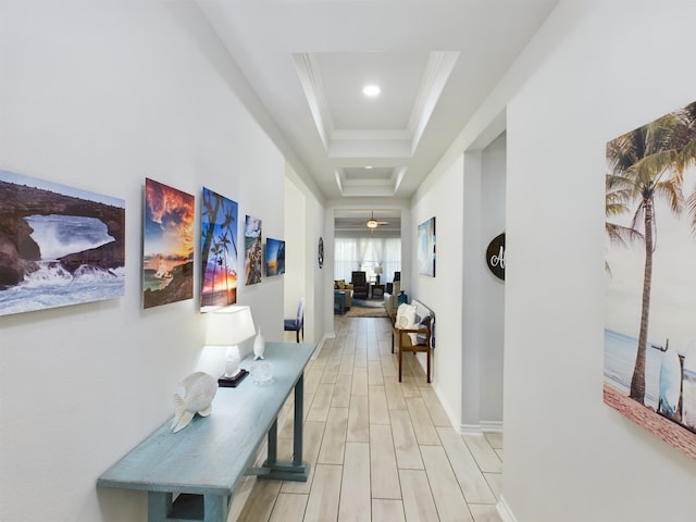 corridor featuring light wood-type flooring, crown molding, and a tray ceiling