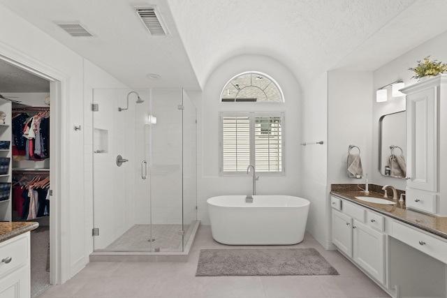 bathroom with a textured ceiling, tile patterned floors, vanity, and vaulted ceiling