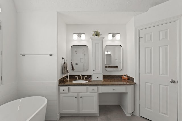 bathroom with a textured ceiling, a washtub, vanity, and tile walls