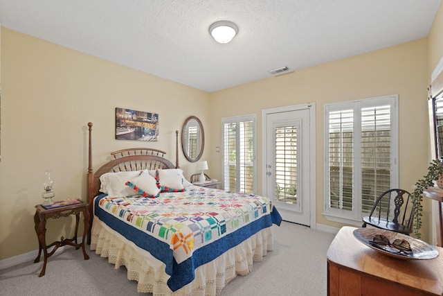 bedroom with a textured ceiling, access to outside, and light colored carpet