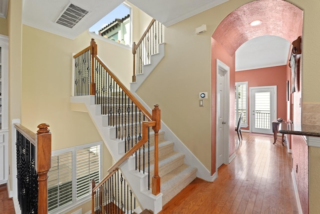 staircase featuring crown molding, wood-type flooring, and lofted ceiling