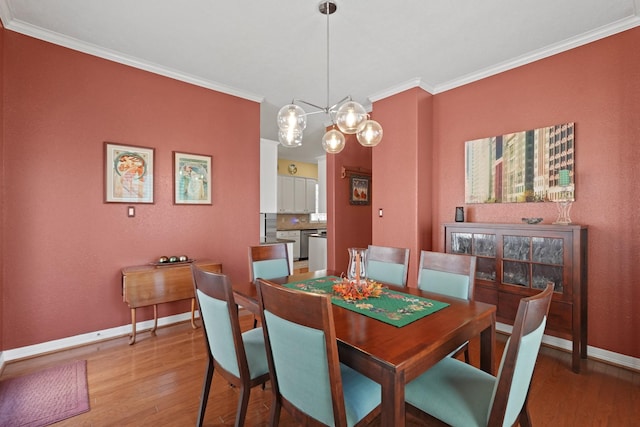 dining space featuring light hardwood / wood-style floors, crown molding, and an inviting chandelier