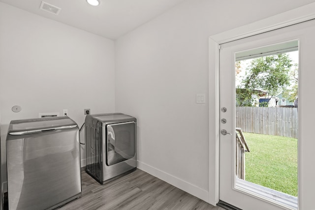 clothes washing area with separate washer and dryer and light wood-type flooring