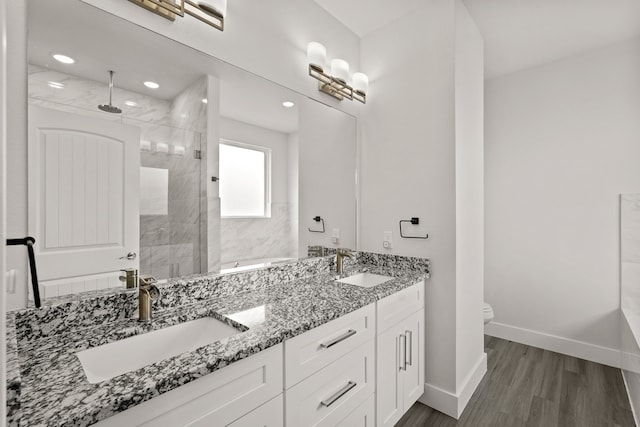 bathroom featuring vanity, hardwood / wood-style floors, tiled shower, and toilet