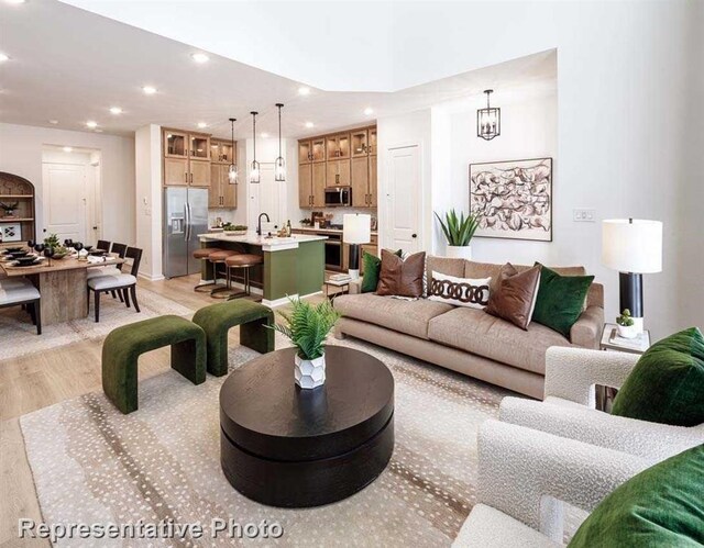 living room featuring a notable chandelier, light hardwood / wood-style floors, and sink