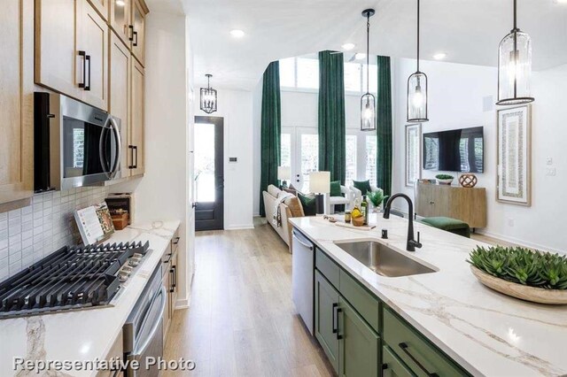 kitchen featuring light hardwood / wood-style floors, pendant lighting, green cabinets, sink, and stainless steel appliances