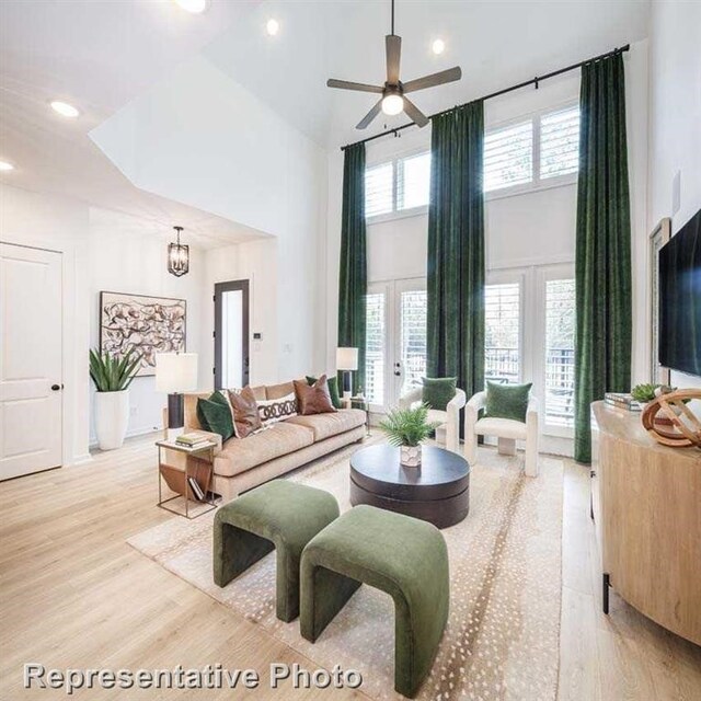 living room featuring light hardwood / wood-style floors, a high ceiling, and ceiling fan