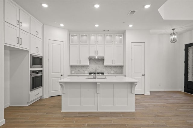 kitchen featuring backsplash, appliances with stainless steel finishes, light countertops, and white cabinetry