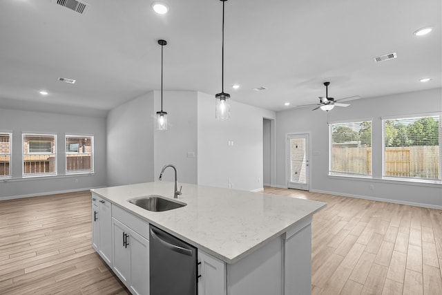 kitchen with light hardwood / wood-style flooring, sink, decorative light fixtures, white cabinetry, and light stone counters