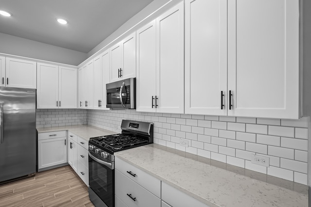 kitchen featuring light hardwood / wood-style flooring, white cabinets, appliances with stainless steel finishes, light stone counters, and tasteful backsplash