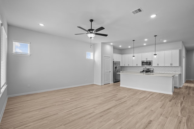 kitchen featuring white cabinetry, a healthy amount of sunlight, stainless steel appliances, and light wood-type flooring