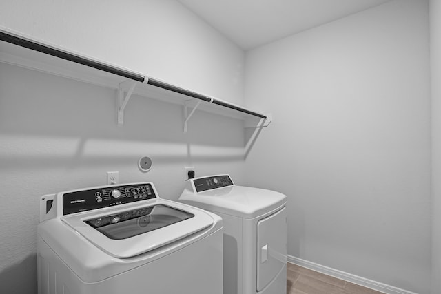 laundry room with light hardwood / wood-style floors and washing machine and dryer