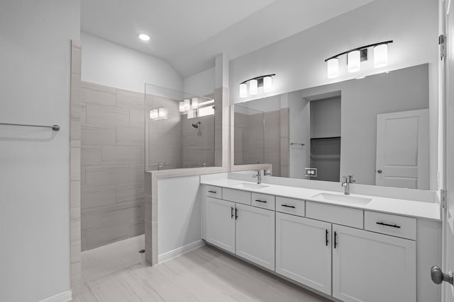 bathroom with vanity, vaulted ceiling, and tiled shower