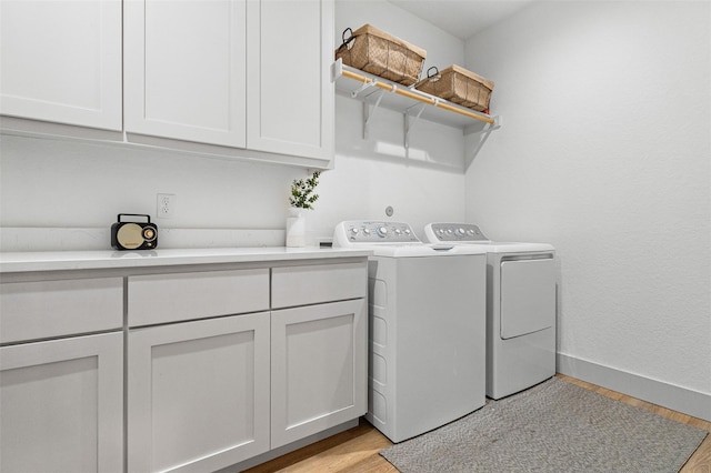 laundry area with cabinets, washer and dryer, and light wood-type flooring