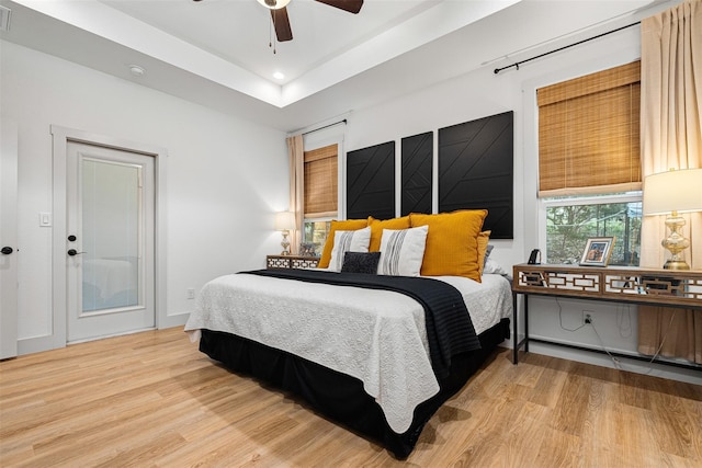 bedroom with a tray ceiling and light hardwood / wood-style flooring