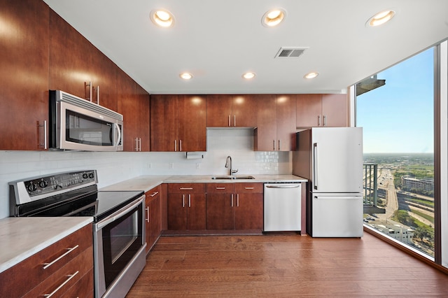 kitchen with sink, appliances with stainless steel finishes, a wealth of natural light, and dark wood-type flooring