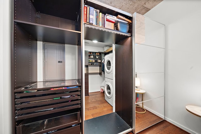 laundry room featuring stacked washing maching and dryer, electric panel, and hardwood / wood-style floors