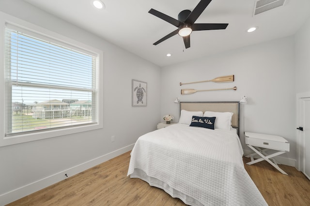 bedroom with hardwood / wood-style flooring, multiple windows, and ceiling fan