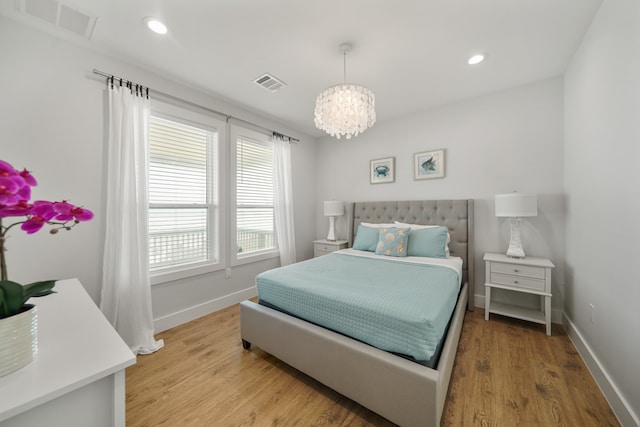 bedroom featuring an inviting chandelier and hardwood / wood-style floors