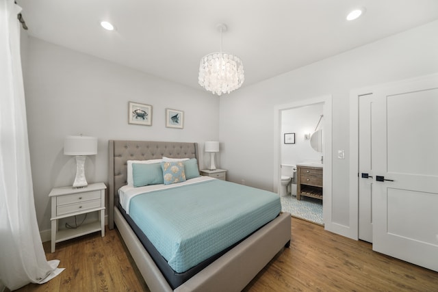 bedroom with wood-type flooring, an inviting chandelier, and ensuite bath