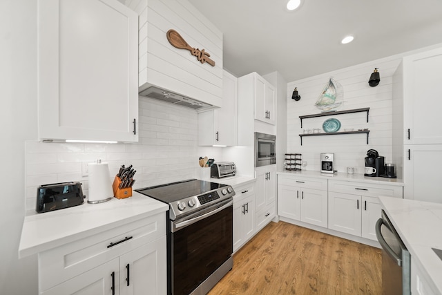 kitchen with premium range hood, appliances with stainless steel finishes, light hardwood / wood-style floors, and white cabinetry