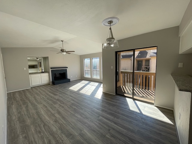 unfurnished living room with vaulted ceiling, ceiling fan with notable chandelier, and dark hardwood / wood-style flooring