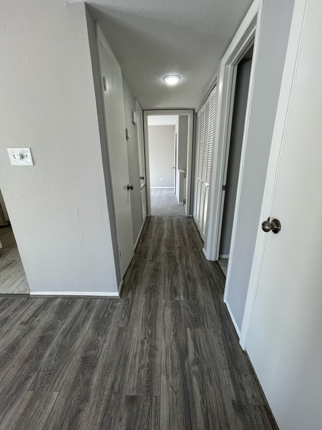 hallway with dark wood-type flooring and a textured ceiling