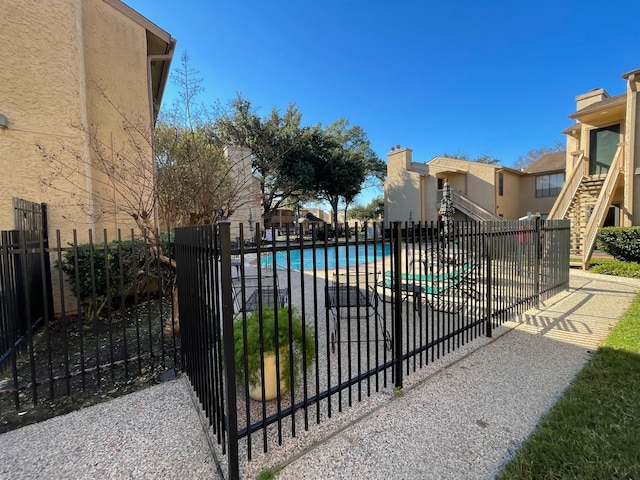 view of gate featuring a community pool and a patio area