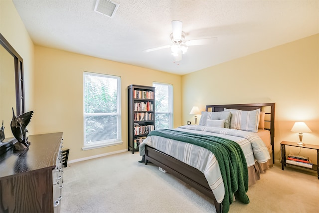 carpeted bedroom featuring ceiling fan and a textured ceiling