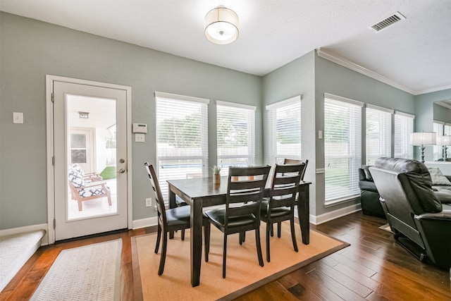 dining space with crown molding, a textured ceiling, dark hardwood / wood-style floors, and a healthy amount of sunlight